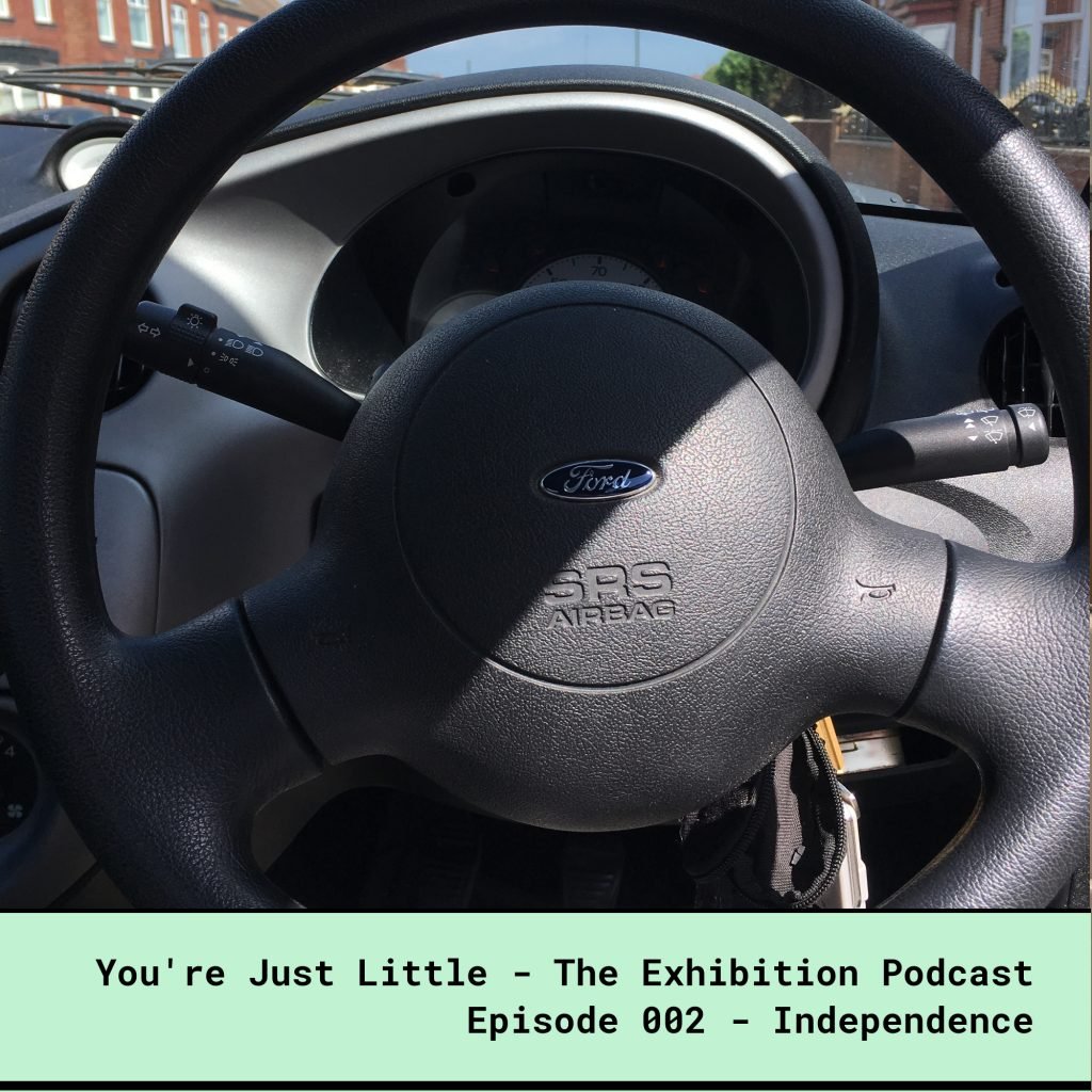 You're Just Little - The Exhibition Podcast - Episode 002 - Independence. Photo by a dwarf person sitting in the driver's seat of an unadapted car.